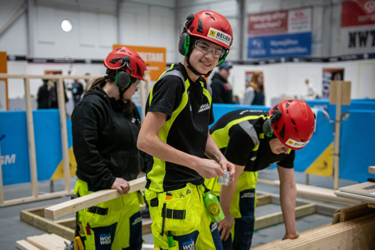 Tre ungdomar hjälps åt att bygga någon ting med reglar
