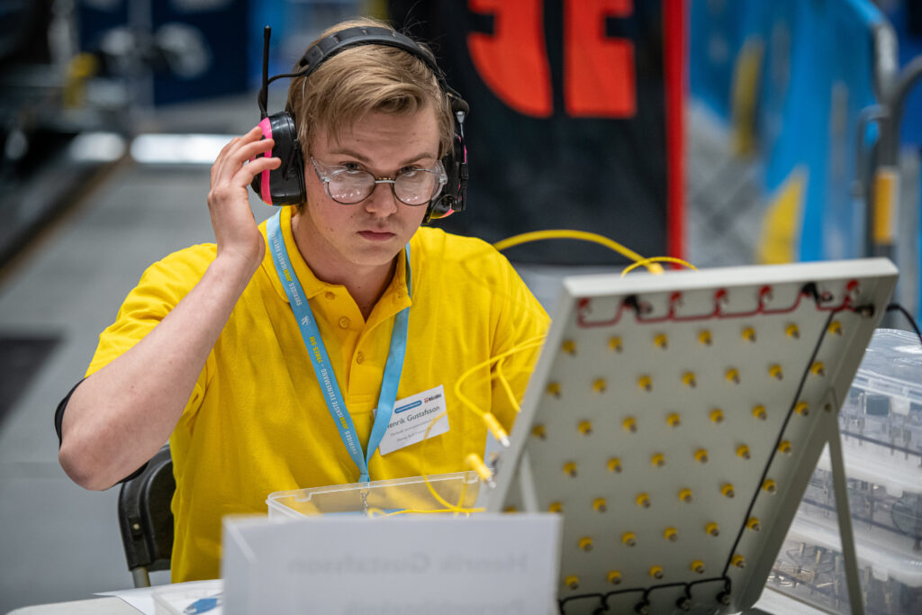 En kille sitter vid ett bord och fokuserar på att lösa ett tekniskt problem av något slag